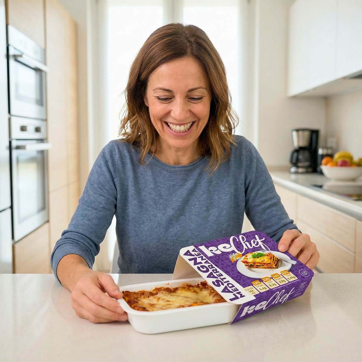 Box X1 settimana piatti pronti: donna felice che apre un piatto pronto di lasagna chetogenica.