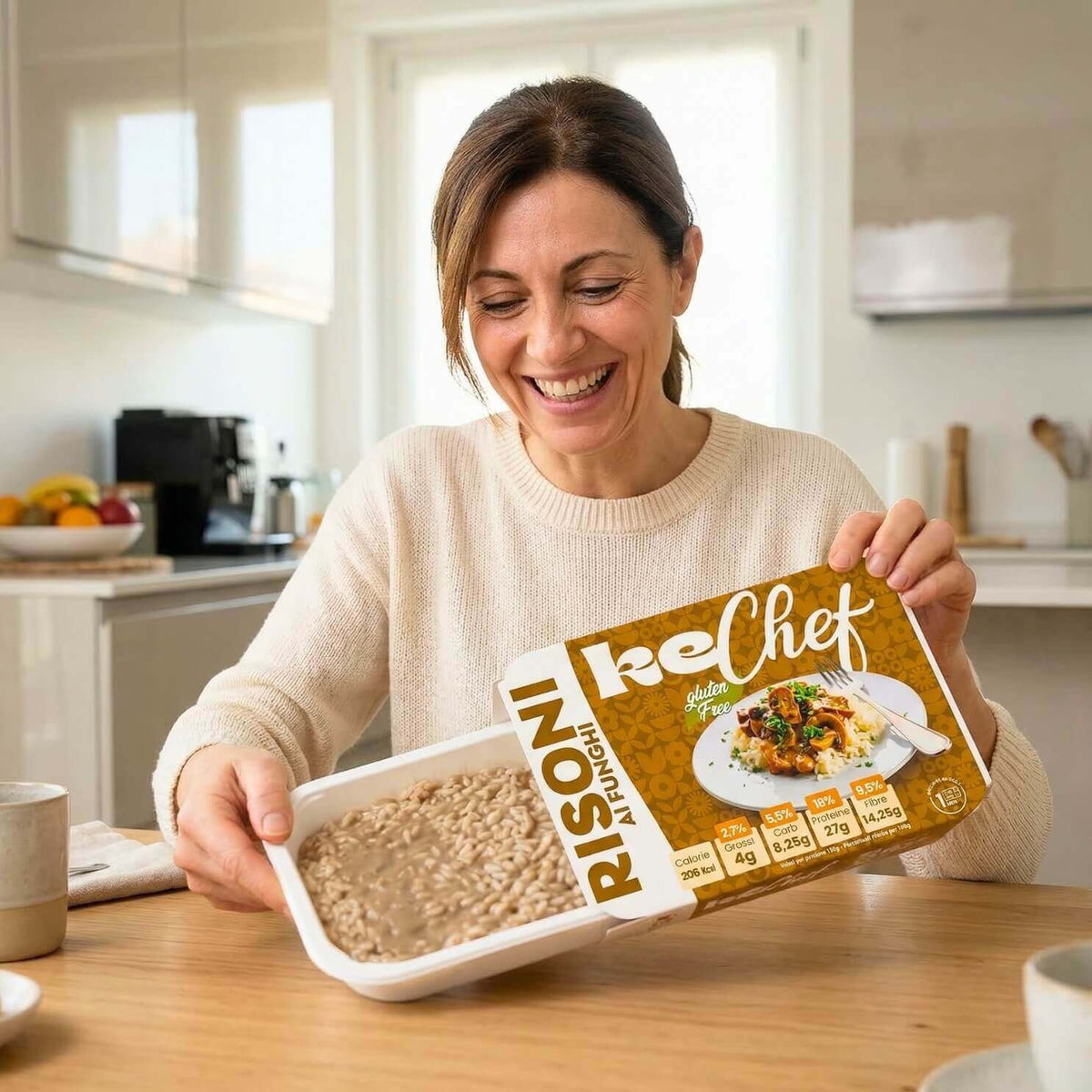 Risoni keChef ai funghi Pronti, donna felice che mostra la confezione del prodotto in cucina.