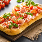 Pinsa proteica con pomodorini, prosciutto e basilico, ideale per dieta chetogenica e alimenti proteici.