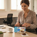 Biscotti proteici Nuvole ricoperti di cioccolato gusto vaniglia mentre una donna li gusta al lavoro.