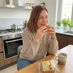 Donna sorridente mentre gusta un saccottino alla crema pasticcera in cucina, ideale per dieta chetogenica.